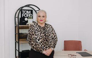 Coach Jennifer Pearce standing confidently by her desk, emphasizing leadership and dental practice profitability.