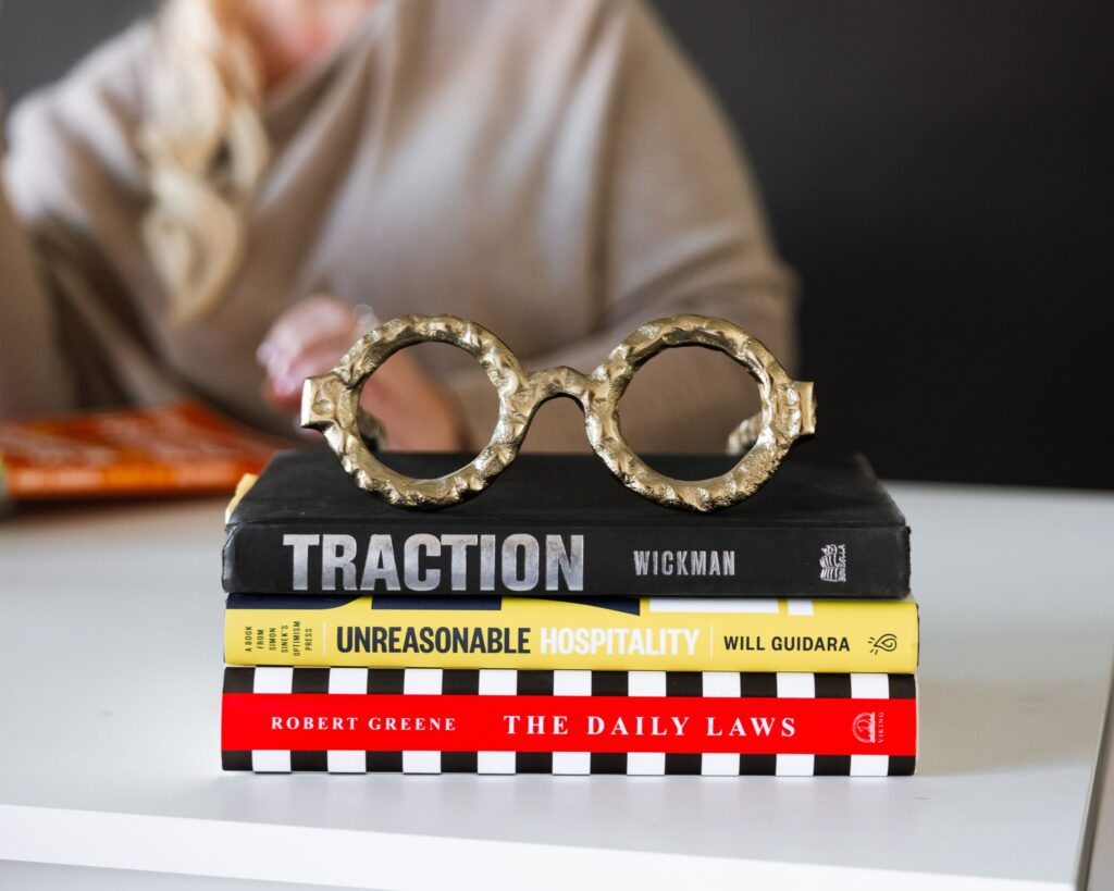 Stack of leadership books including Traction and Unreasonable Hospitality for dental practice leadership development